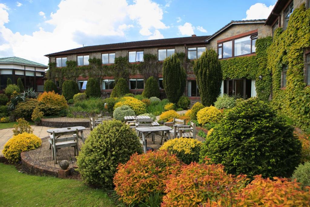 ein Gebäude mit Tischen und Stühlen in einem Garten in der Unterkunft Best Western Plus Centurion Hotel in Midsomer Norton