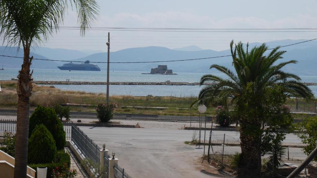 a beach with palm trees and ships in the water at Villa with the view of Palamidi and Bourtzi in Nafplio