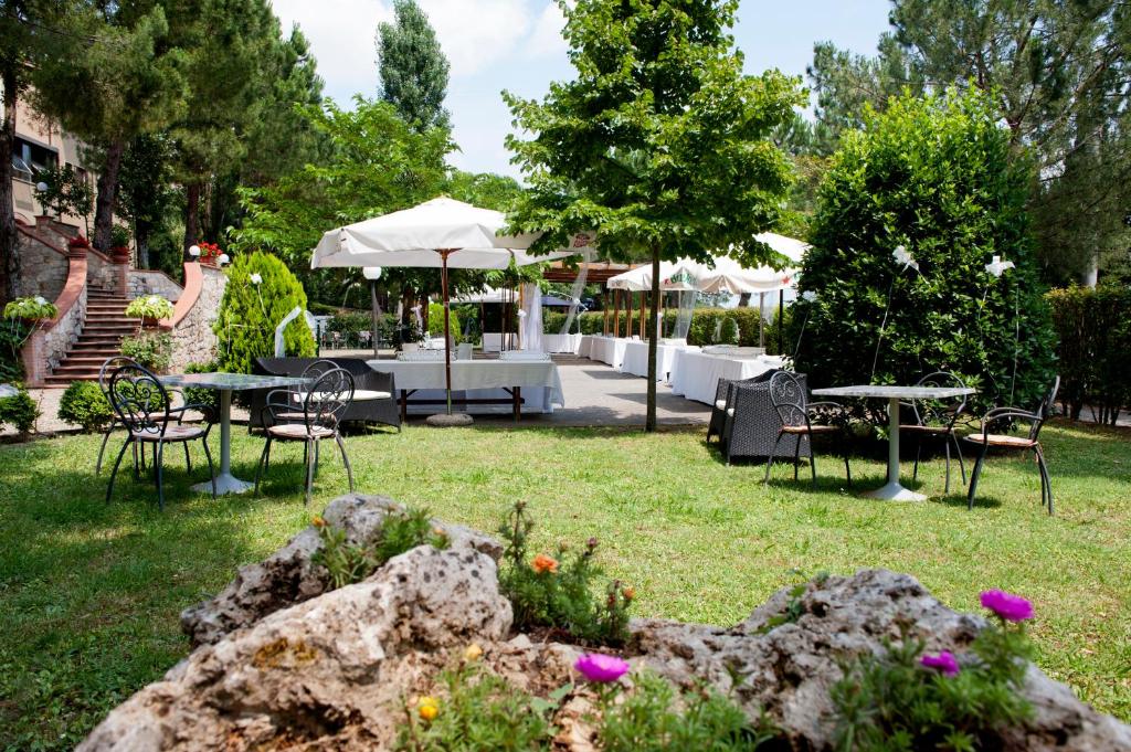 kobieta stojąca na podwórku ze stołami i krzesłami w obiekcie Hotel Ristorante Il Pino w mieście Chiusi