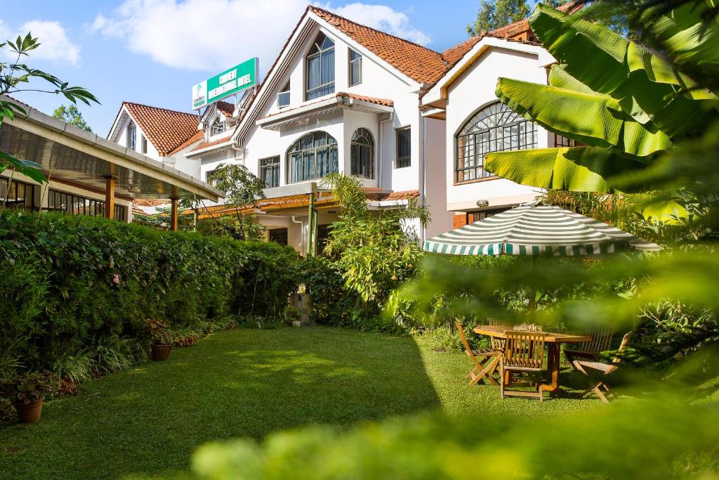 a house with a table and an umbrella in the yard at Convent International Hotel- Nairobi in Nairobi