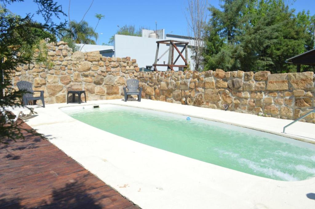 een zwembad met 2 stoelen naast een stenen muur bij Hostería San Benito in Concordia