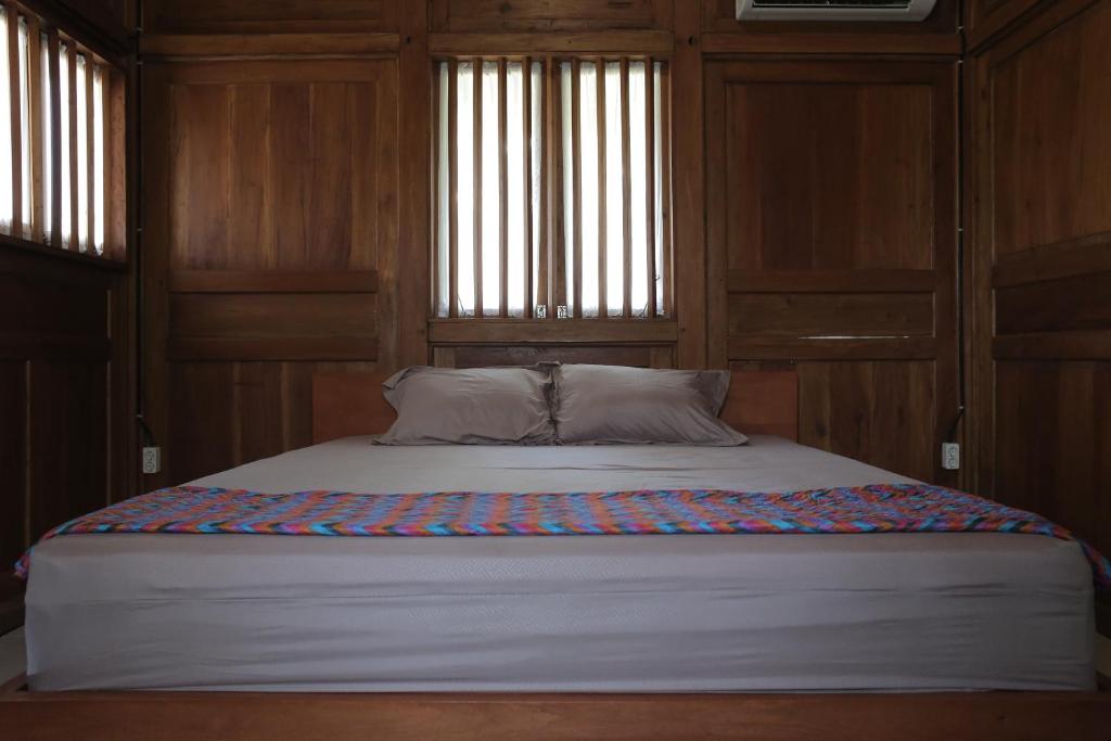a bed in a room with wooden walls and windows at Keboen Ndalem Homestay in Semarang