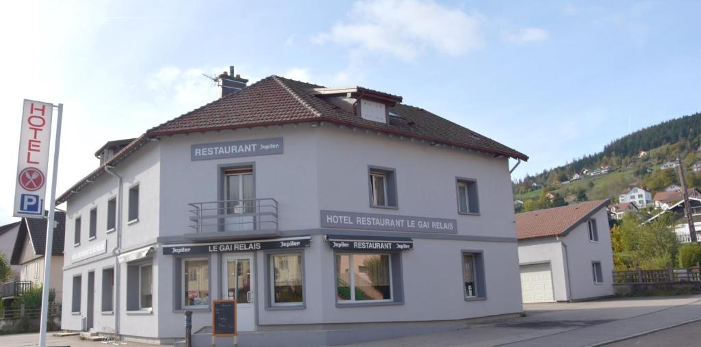 biały budynek na rogu ulicy w obiekcie Hotel Gai Relais w mieście Gérardmer