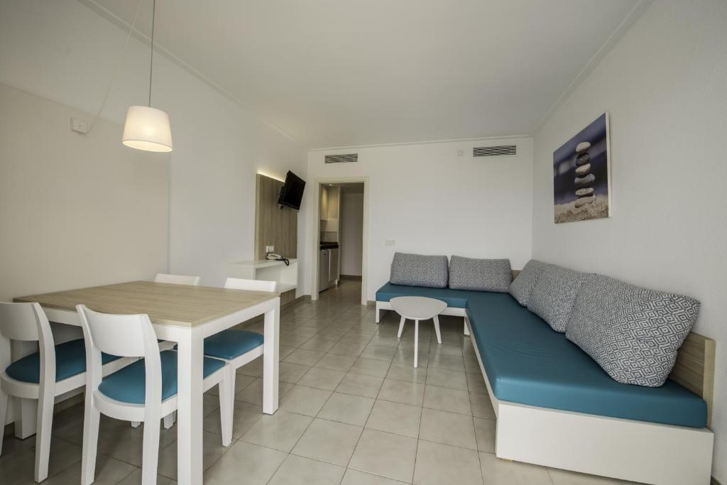 Apartamentos La Santa Maria في كالا مييور: غرفة معيشة مع أريكة زرقاء وطاولة