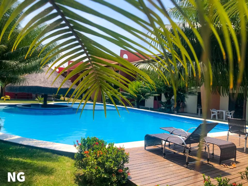 una piscina con 2 sillas y una palmera en Conchas e Corais - Village Paraíso, en Barra Grande