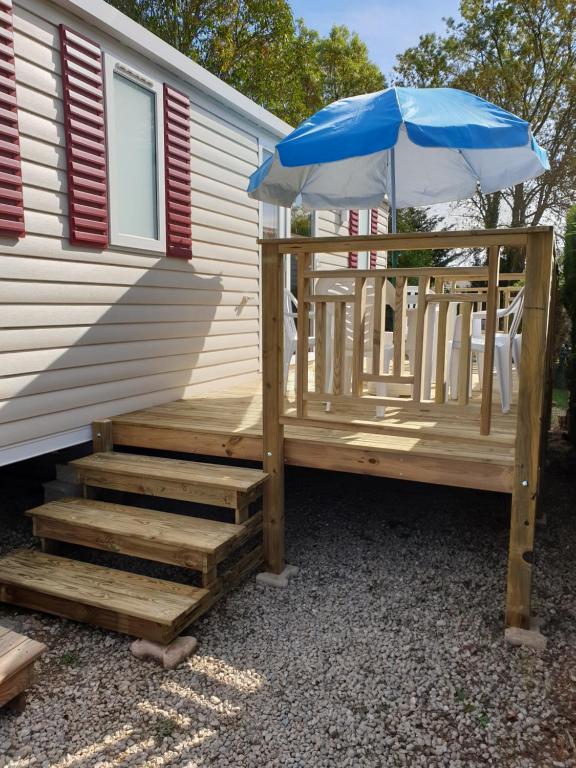 una terraza de madera con sombrilla y sillas en Mobil home 3 chambres en Lattes