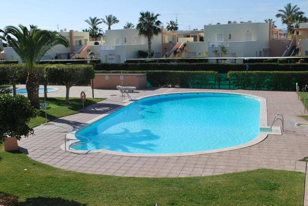 a large swimming pool in a yard with palm trees and buildings at Casa Grace Naturist Apartment Vera in Vera
