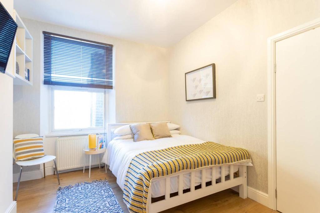 a small bedroom with a bed and a window at Modern 1 Bed Studio Flat in West Kilburn by Queen's Park for 2 people in London