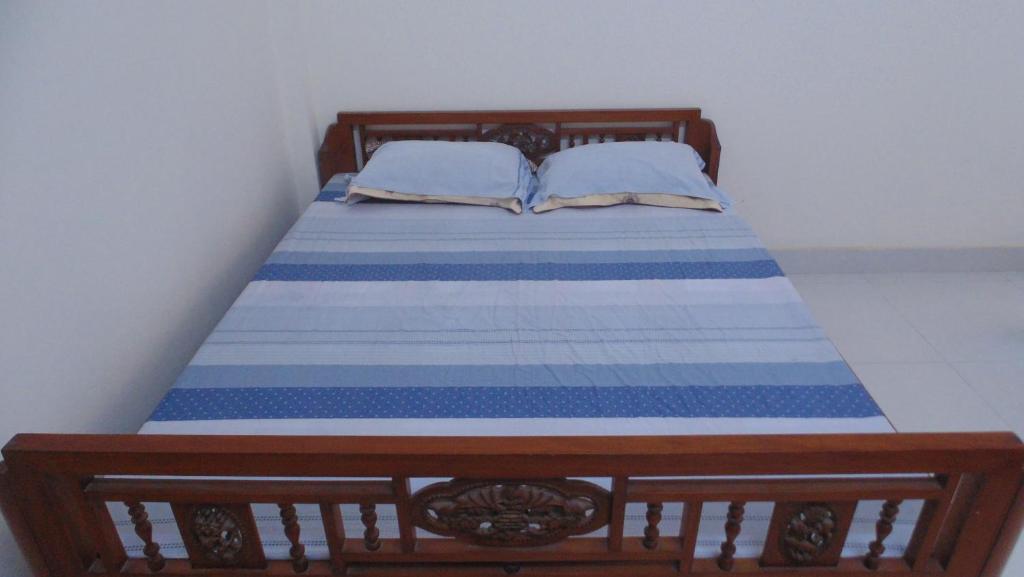 un letto in legno con lenzuola e cuscini blu e bianchi di Homestay Nam Dong a Hanoi