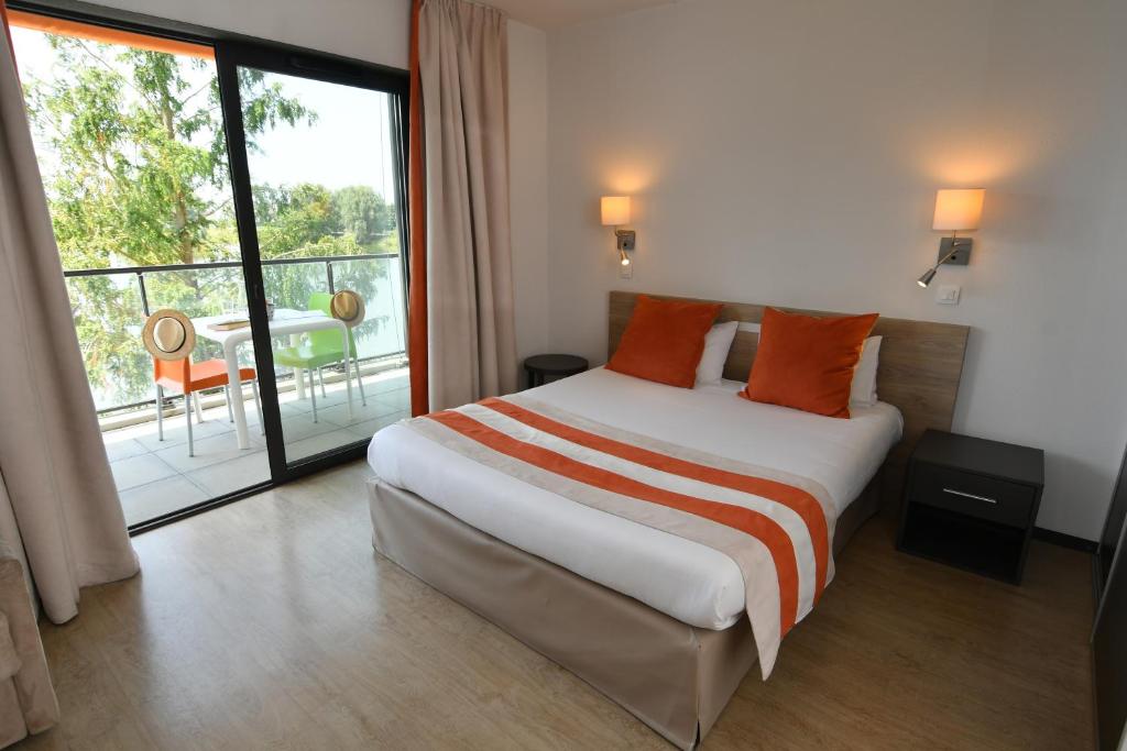 une chambre avec un grand lit et un balcon dans l'établissement Appart-Hôtel Mer & Golf City Bordeaux - Bruges, à Bruges
