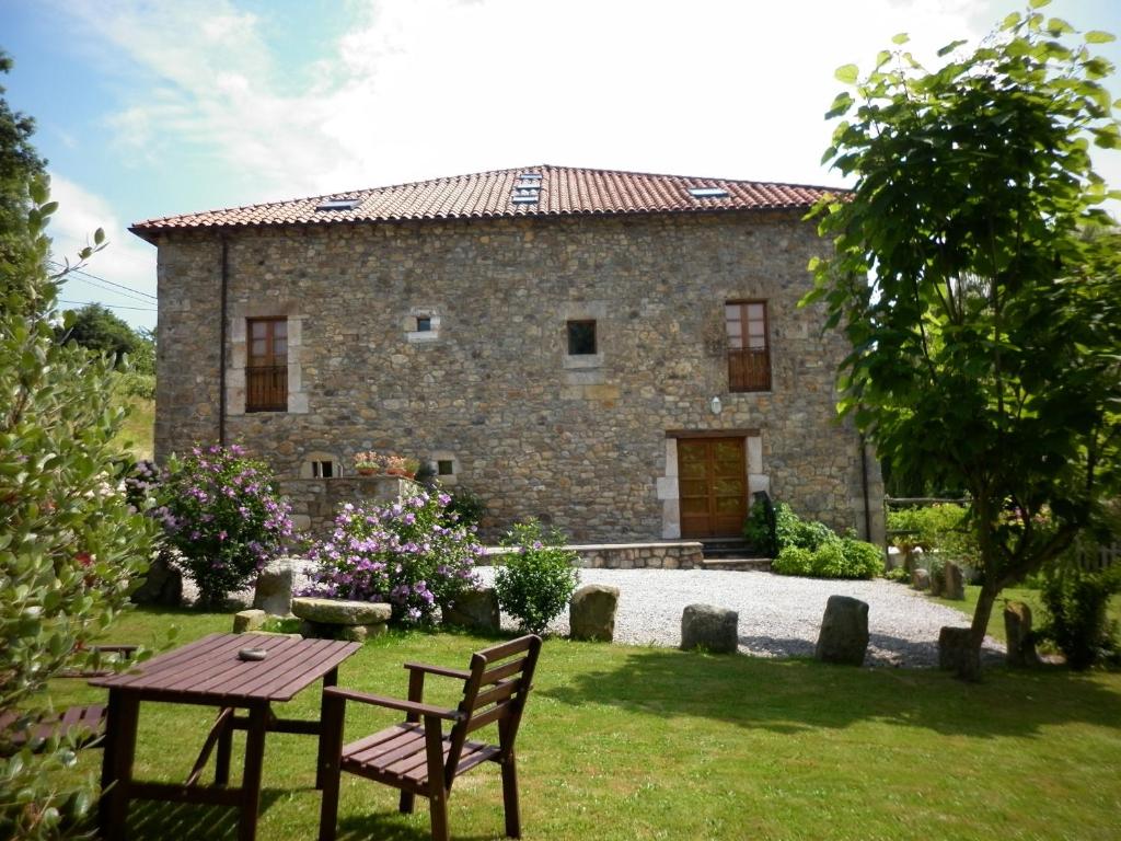 a stone house with a table and chairs in the yard at Las Navedas in Santibáñez de Villacarriedo