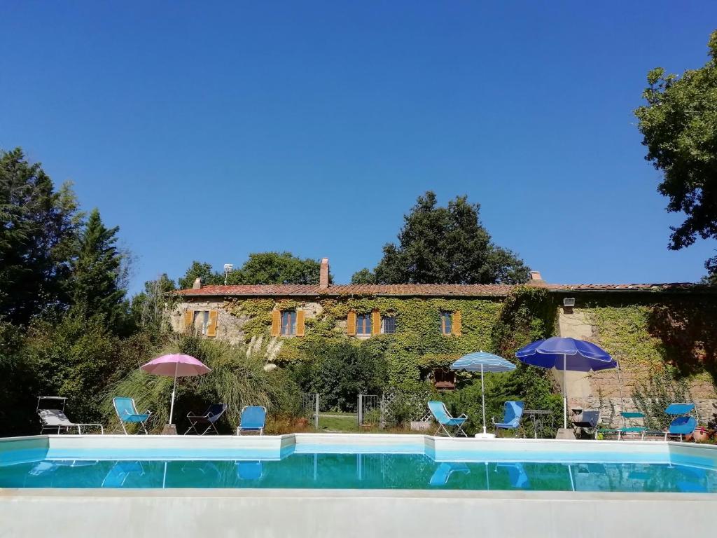 una piscina con sillas y sombrillas frente a un edificio en Podere Poggio Corbo, en Chiusdino