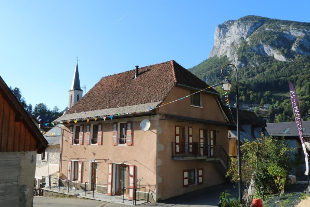 a building in front of a mountain with a church at Le postillon REZ in Saint-Pierre-dʼEntremont