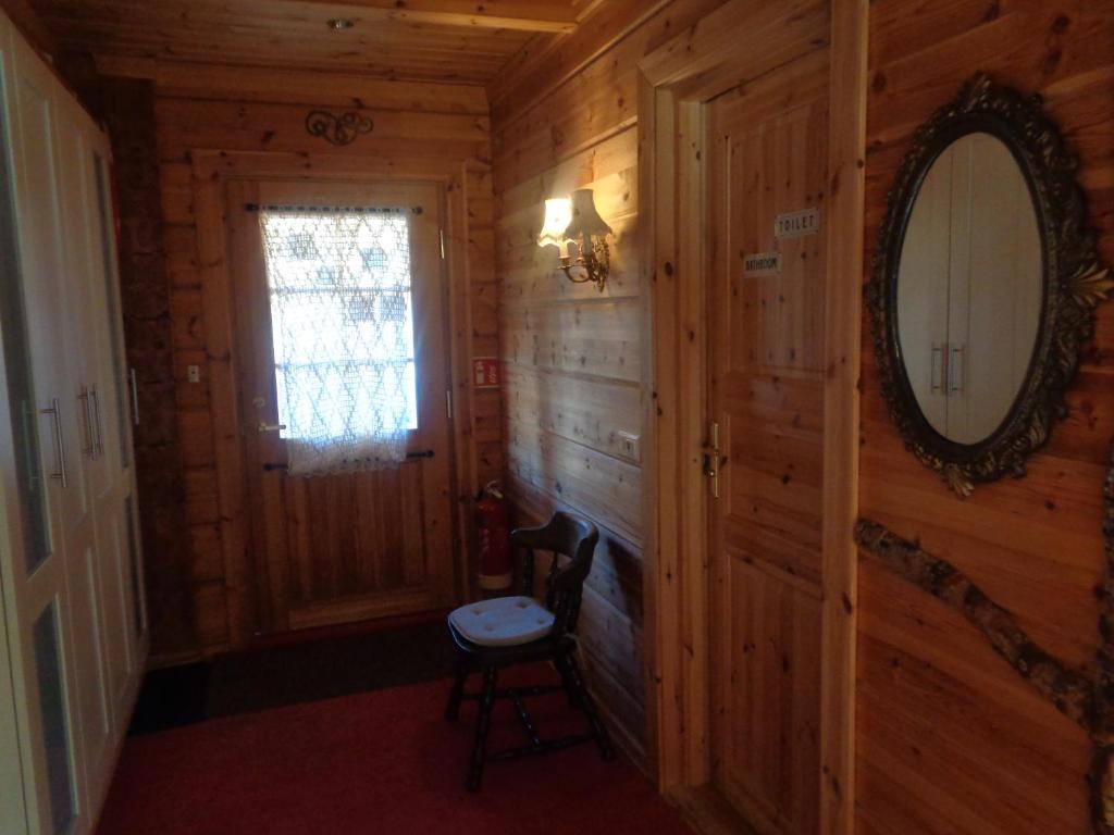 a hallway in a log cabin with a mirror and a chair at Family Home in Fáskrúðsfjörður