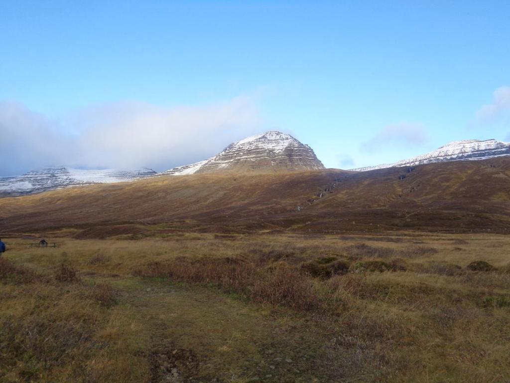 a mountain with snow covered mountains in a field at Family Home in Fáskrúðsfjörður