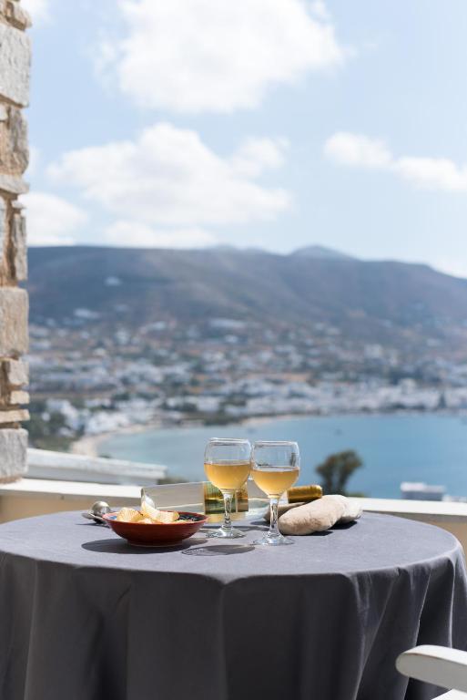 two glasses of wine sitting on a table with a view at Krotiri Bay -adults only in Parikia