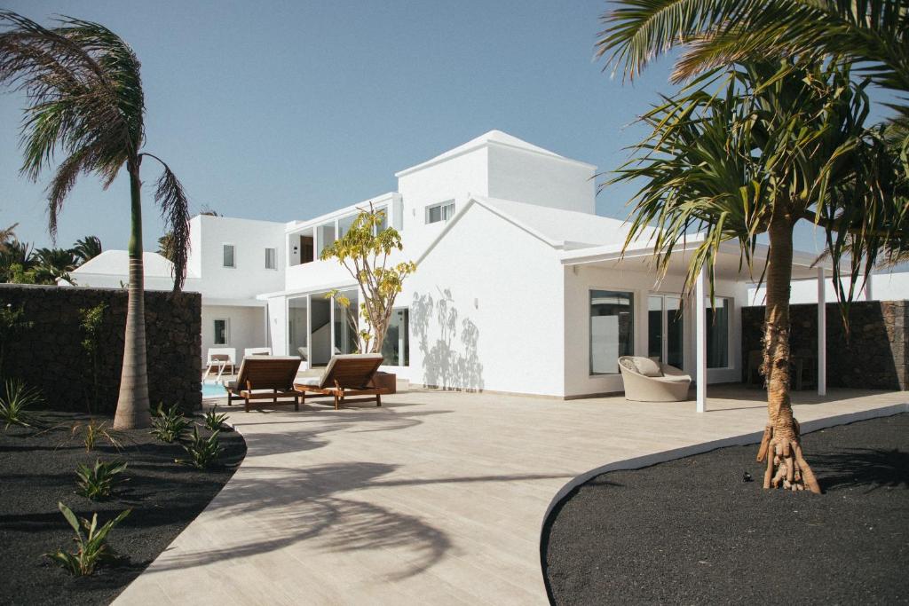 a white house with palm trees in front of it at ALAVA SUITES in Costa Teguise