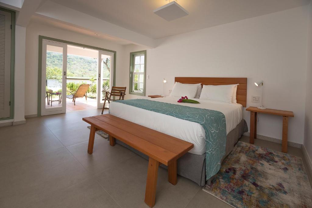 um quarto com uma cama grande e um banco de madeira em Pouso Alforria em Tiradentes