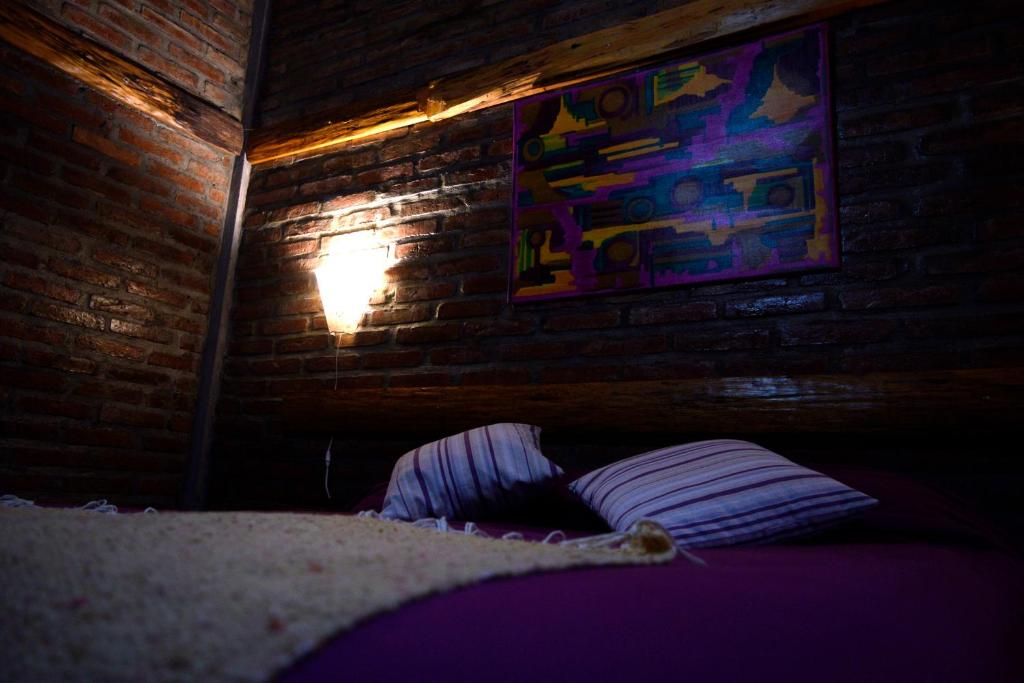 Habitación oscura con cama y pared de ladrillo en Wau Purul en Cholila