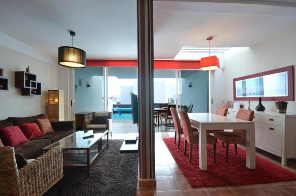 a living room with a table and a dining room at Villa Mariña piscina climatizada opcional y 2 bicis gratuitas in Playa Blanca