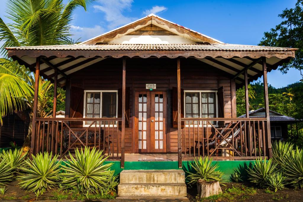 een klein houten huis met een veranda bij Picard Beach Cottages in Portsmouth