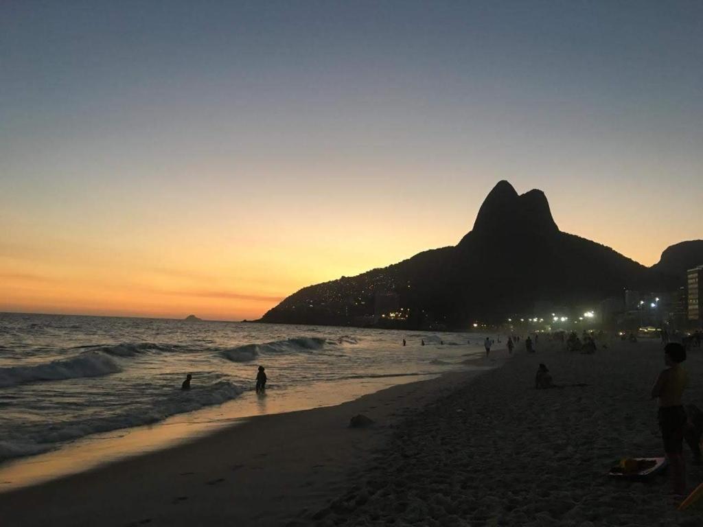 un grupo de personas en la playa al atardecer en Apartamento Familiar 3 quartos - Leblon, en Río de Janeiro