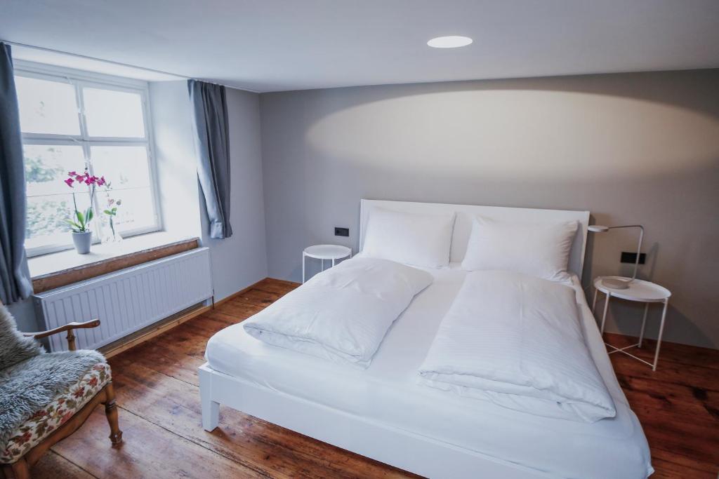 ein Schlafzimmer mit einem weißen Bett und einem Fenster in der Unterkunft Clara Erdgeschosswohnung im Jüdischen Viertel in Hohenems