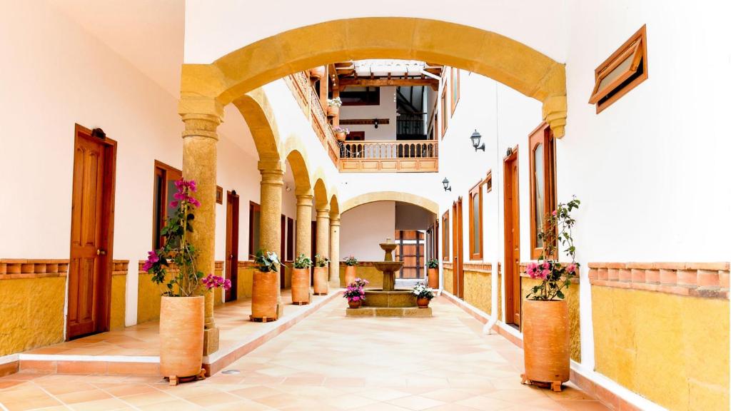 a hallway in a building with potted plants at Hospederia Villa de los Sáenz in Villa de Leyva
