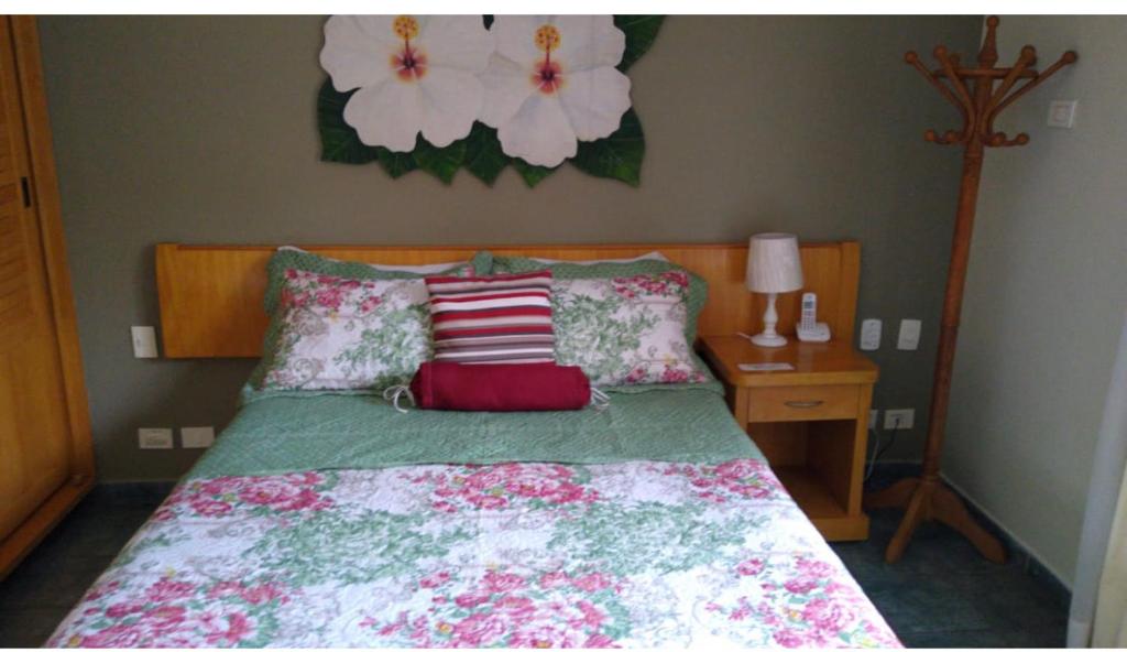 1 dormitorio con 1 cama con flores en la pared en Apto no IlhaFlat em frente Mar en Ilhabela