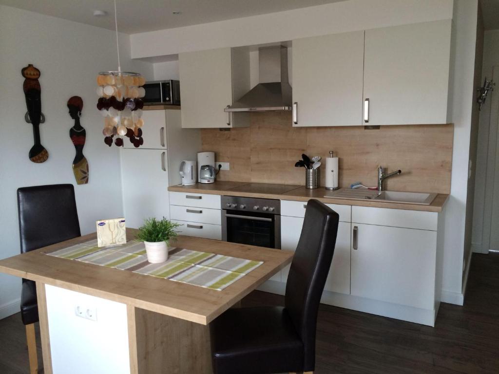 a kitchen with white cabinets and a wooden table at Moderne-Ferienwohnung-in-ruhiger-Lage in Quickborn