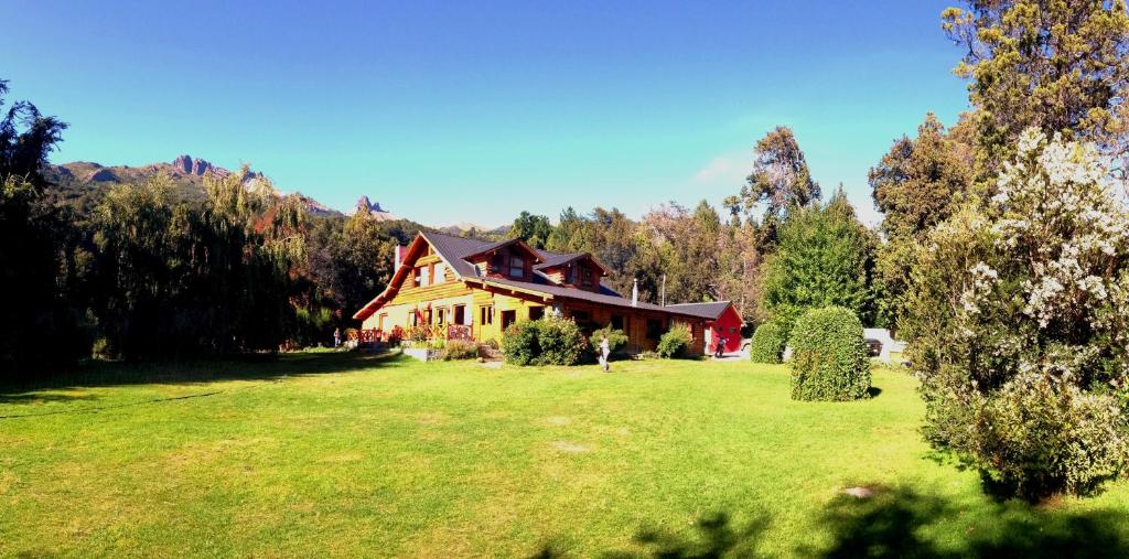 una casa en un gran campo de césped con árboles en Vulcanche en Villa Traful