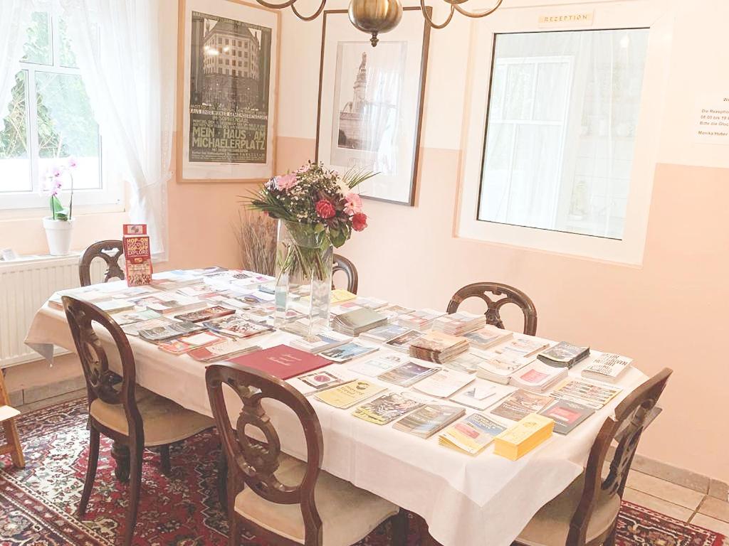 a dining room table with books on it with chairs at Pension Huber in Klosterneuburg