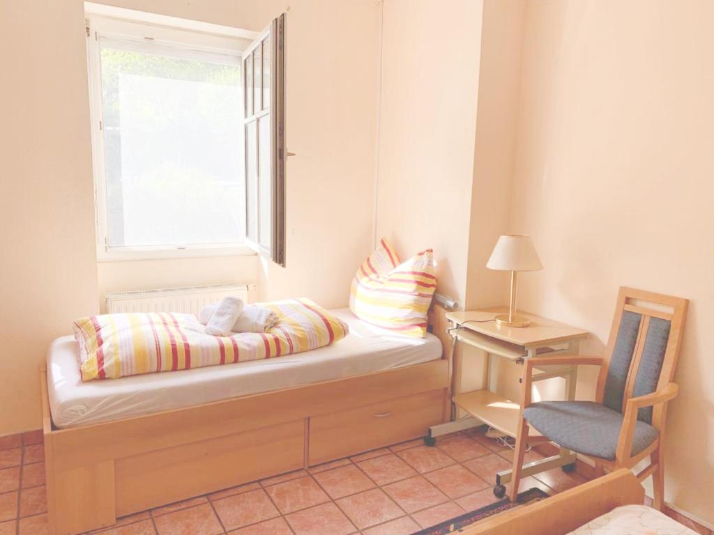 a bedroom with a bed and a window and a chair at Pension Huber in Klosterneuburg