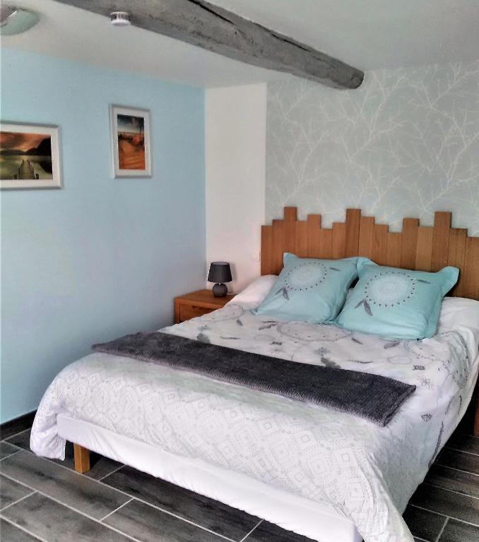 une chambre avec un grand lit avec une tête de lit en bois dans l'établissement Au Rêve en Somme, à Hautvillers-Ouville