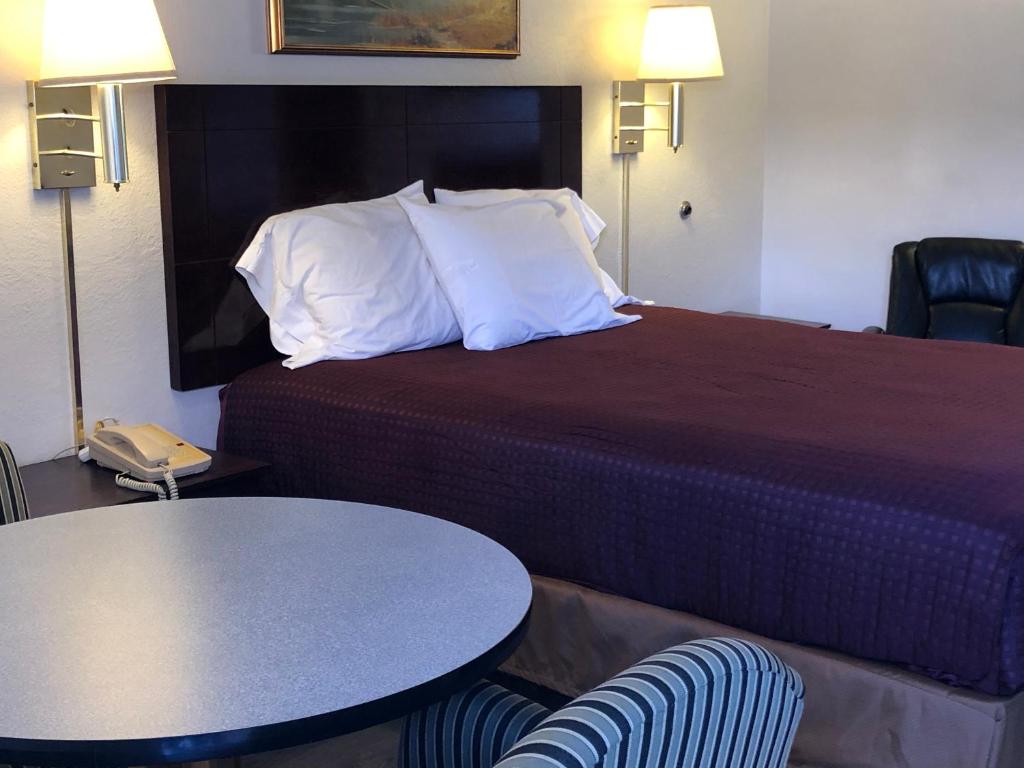 Habitación de hotel con cama, mesa y sillas en Economy Inn Alamogordo, en Alamogordo