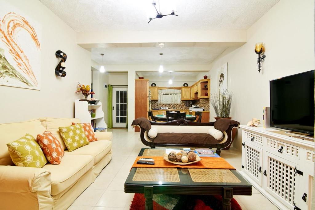 a living room with a couch and a tv at Atlantic Breeze Apartments, Canouan Island in Canouan