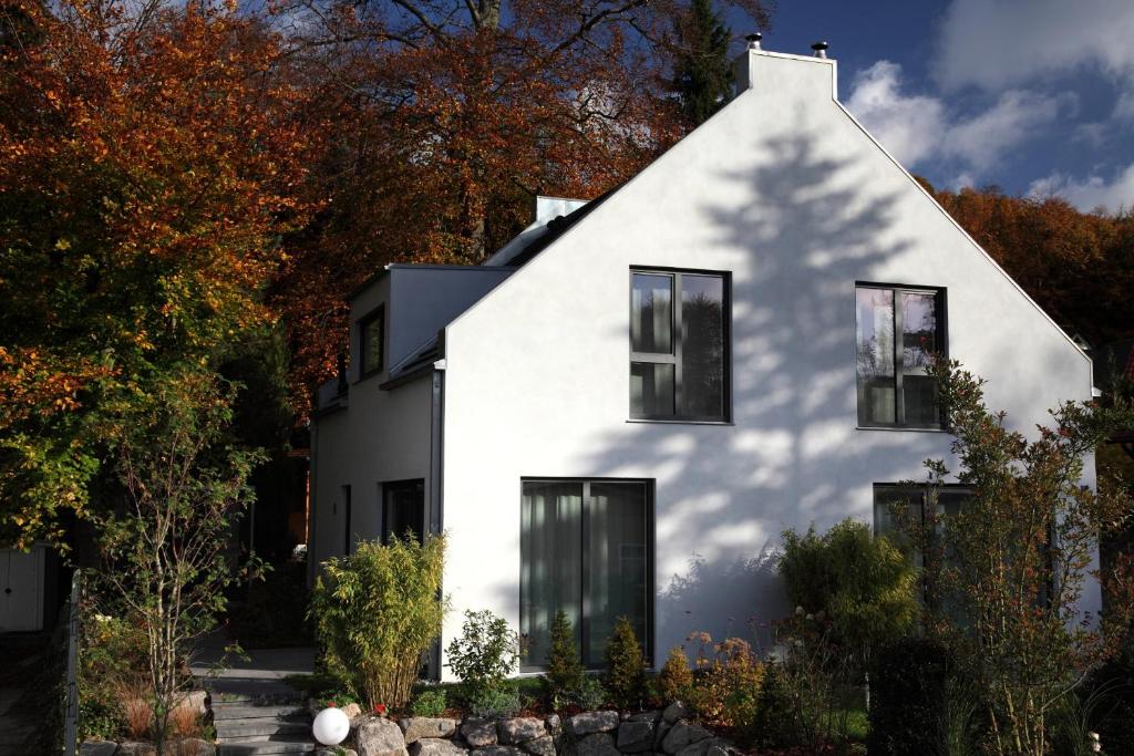 a white house with black windows and trees at Ferienhaus Sonnensteg 23 in Ostseebad Sellin