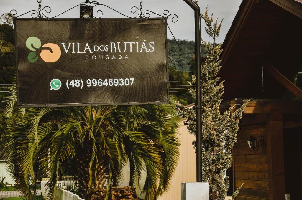 una señal frente a un edificio con una palmera en Pousada Vila dos Butias, en Urubici