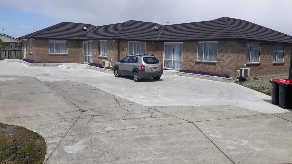 a car parked in a parking lot in front of a house at South City Accommodation unit 3 in Invercargill