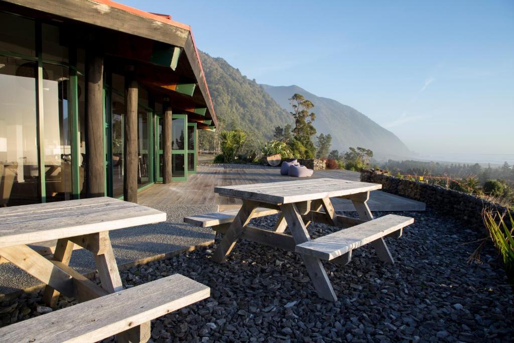 two picnic tables outside of a building with mountains in the background at Rataview in Barrytown