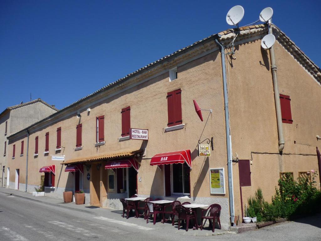 een gebouw met tafels en stoelen in een straat bij Hôtel Etape in Les Omergues