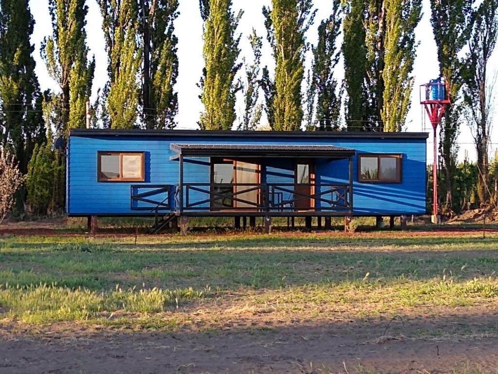 una casita azul al lado de un campo en Chacra Arana cabaña de campo, en Villa Regina