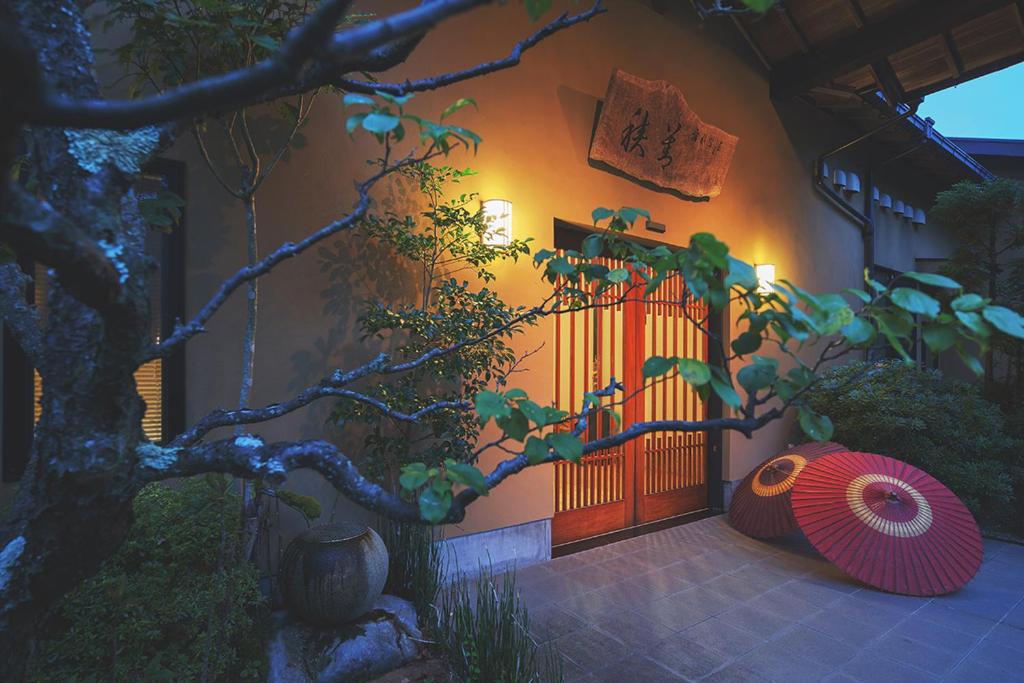 una casa con una puerta y un árbol delante de ella en Hanare Yado Yosizumi en Izu