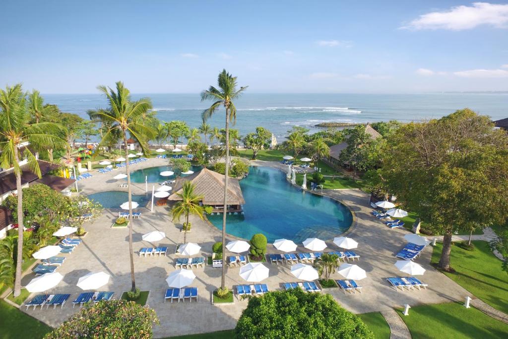 a beach area with umbrellas, chairs and tables at Discovery Kartika Plaza Hotel in Kuta