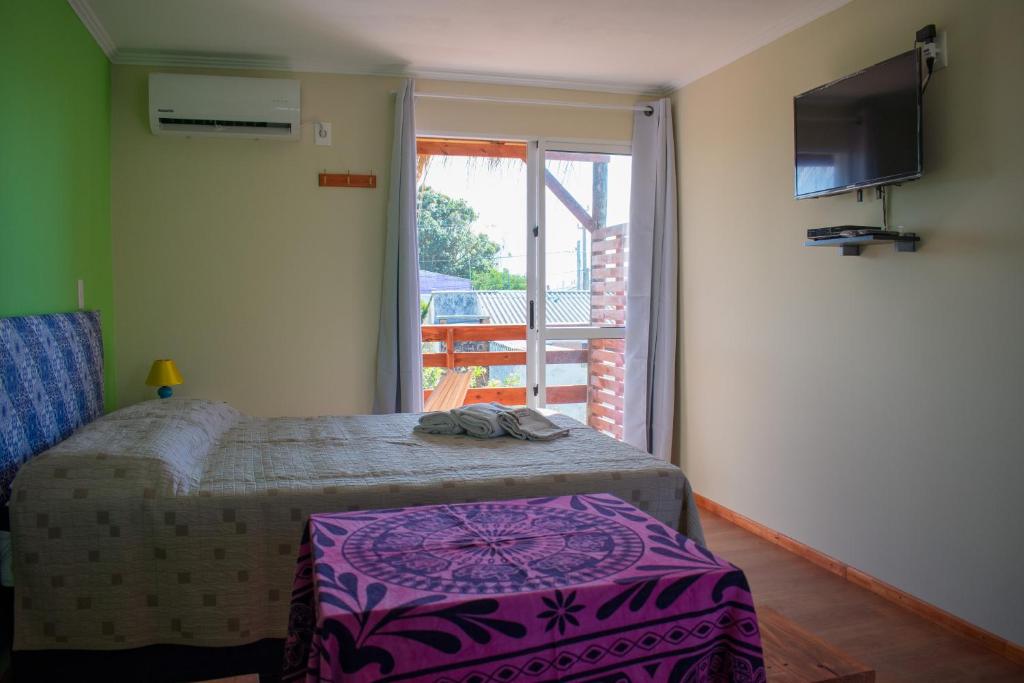 Habitación con cama, TV y balcón. en Aparts Dunas de Valizas, en Barra de Valizas
