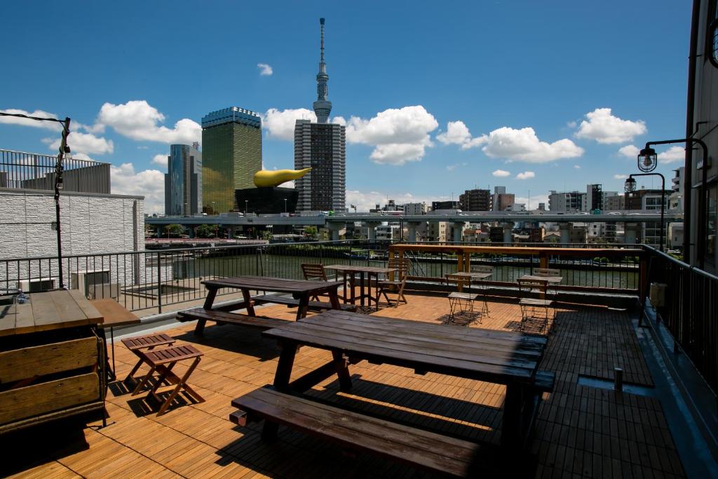 a deck with picnic tables and chairs and a city skyline at Hostel Chapter Two Tokyo in Tokyo