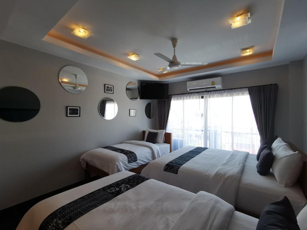 a hotel room with two beds and a window at The Besavana Phuket - SHA Extra Plus in Phuket Town