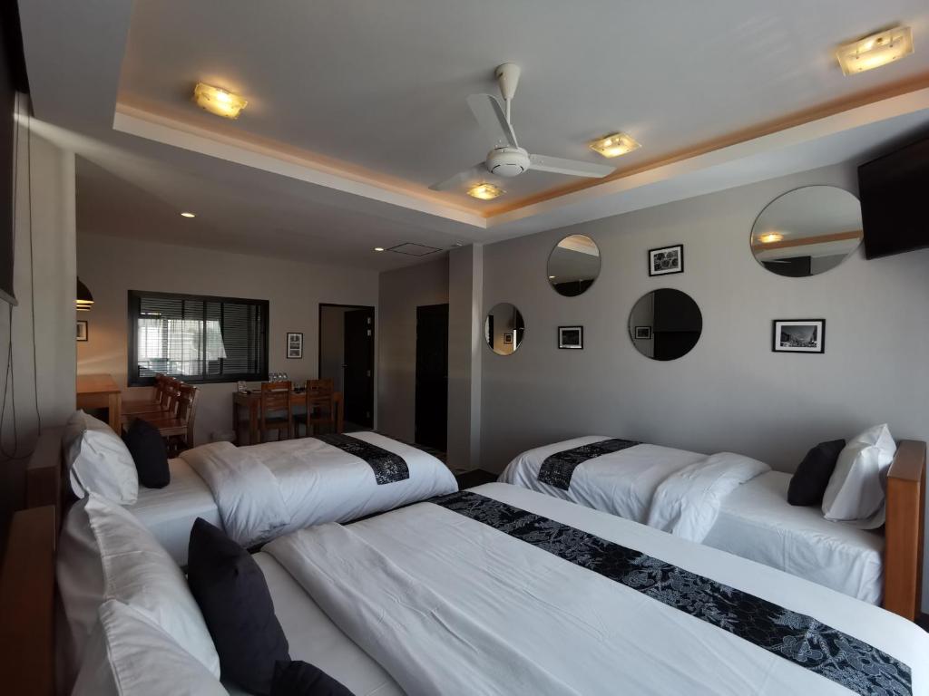 a room with four beds and a dining room at The Besavana Phuket - SHA Extra Plus in Phuket Town