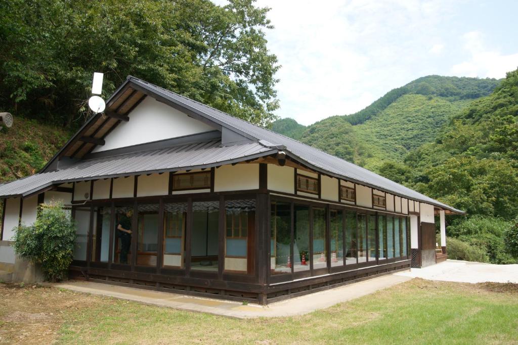a building with windows and mountains in the background at せとうち古民家ステイズHiroshima 不老仙 in Shōbara