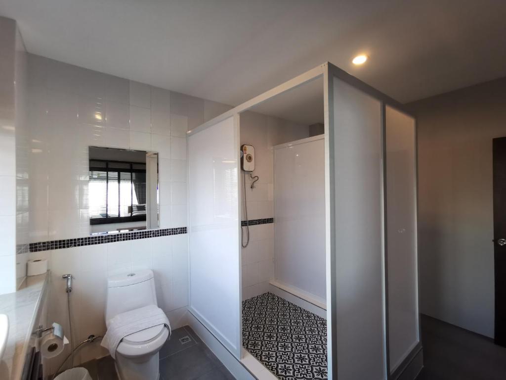 a white bathroom with a toilet and a shower at The Besavana Phuket - SHA Extra Plus in Phuket Town